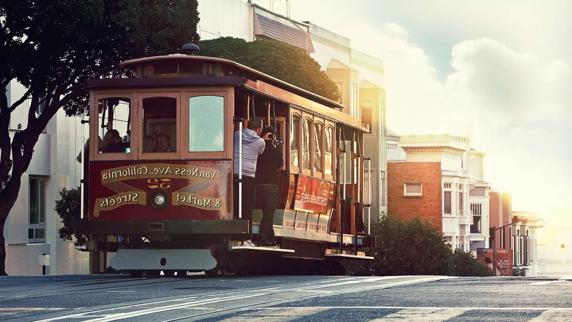 Un tranvía rodea una colina en San Francisco con pasajeros mirando por la ventana.